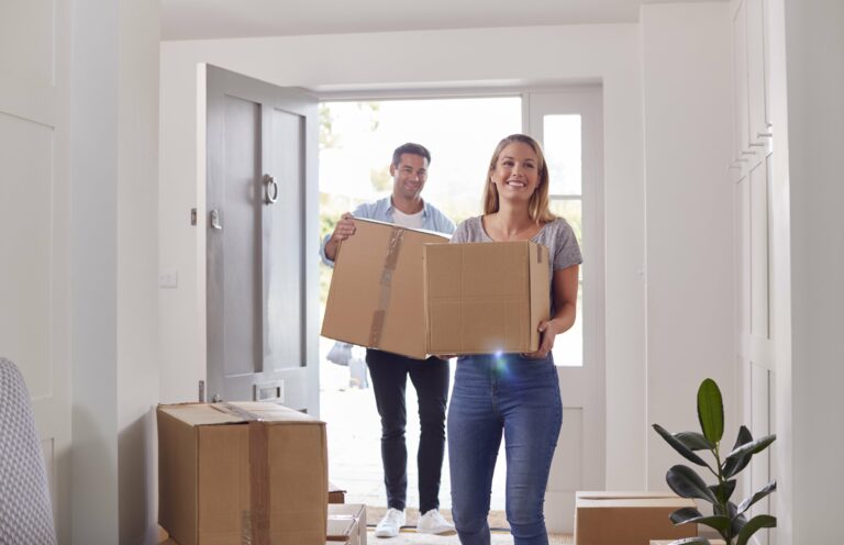 People moving boxes into a house